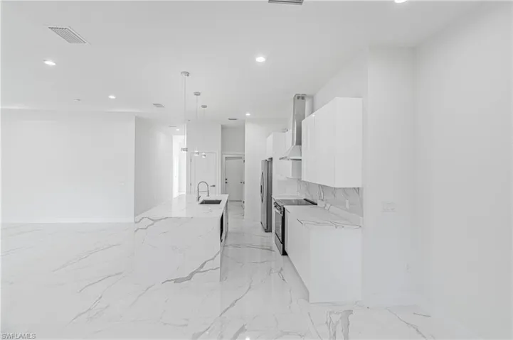 Kitchen with white cabinetry, stainless steel appliances, light stone counters, modern cabinets, and recessed lighting