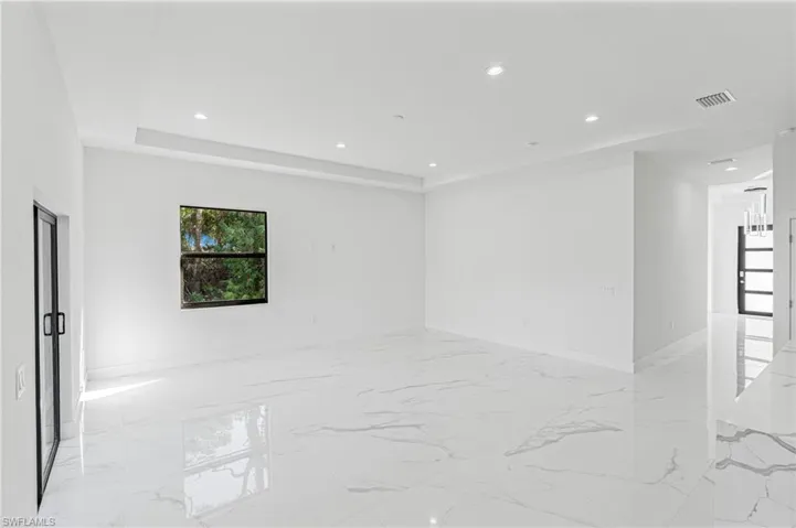 Unfurnished room with recessed lighting, light marble finish floors, and a raised ceiling