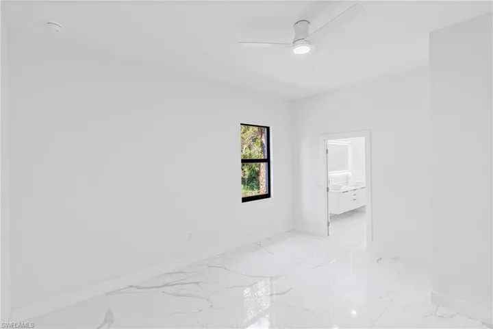 Empty room featuring a ceiling fan and light marble finish floors