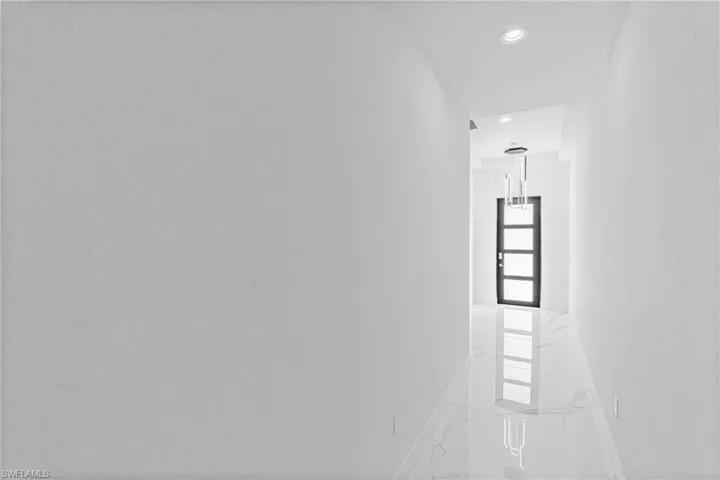 Hallway with marble tiled floors, recessed lighting, and a textured wall