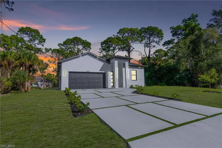 View of front of house featuring stucco siding, an attached garage, a front lawn, and concrete driveway