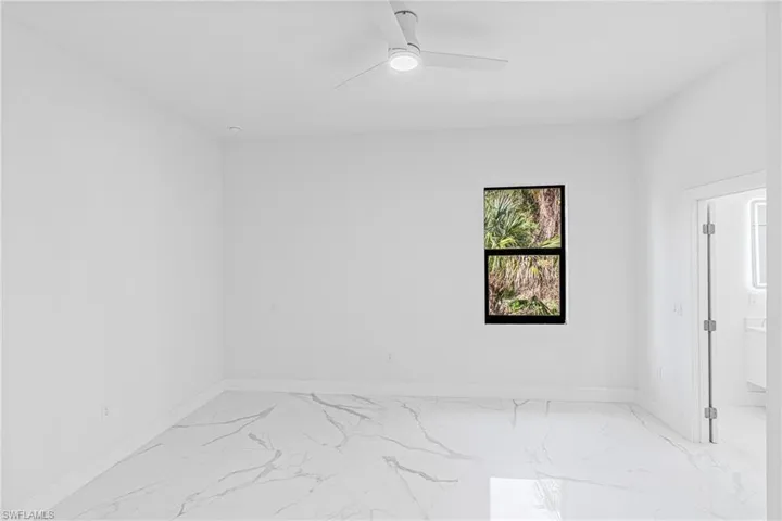 Unfurnished room featuring light marble finish flooring and ceiling fan
