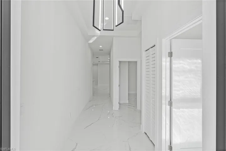 Corridor with light marble finish floors and recessed lighting