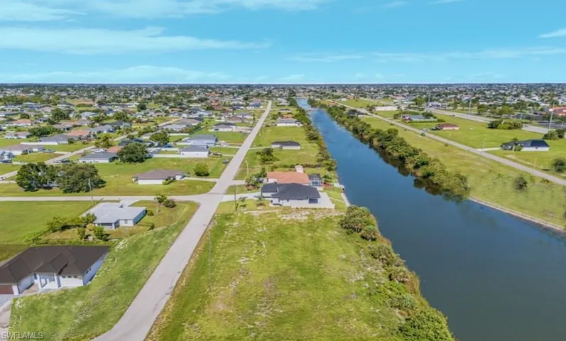 Aerial view of property's location featuring a nearby body of water and nearby suburban area
