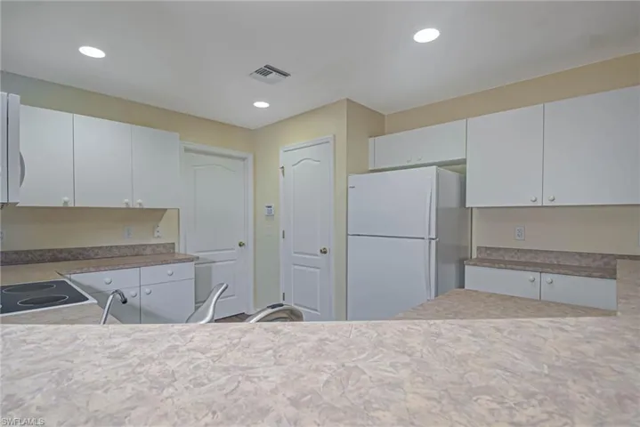 Kitchen featuring white fridge and white cabinets