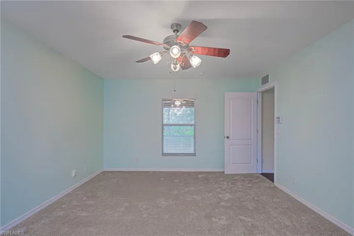 Empty room with ceiling fan and light colored carpet