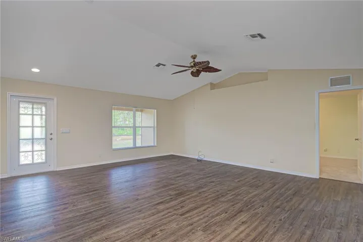 Unfurnished room with vaulted ceiling, ceiling fan, and dark hardwood / wood-style floors