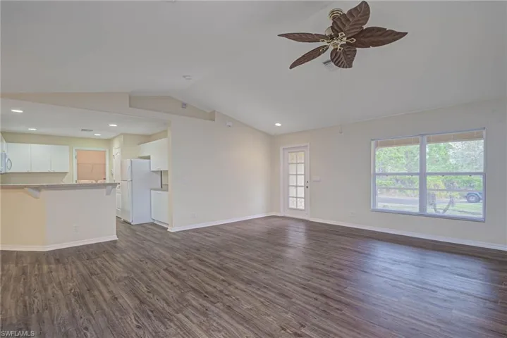 Unfurnished living room with ceiling fan, vaulted ceiling, and dark hardwood / wood-style flooring