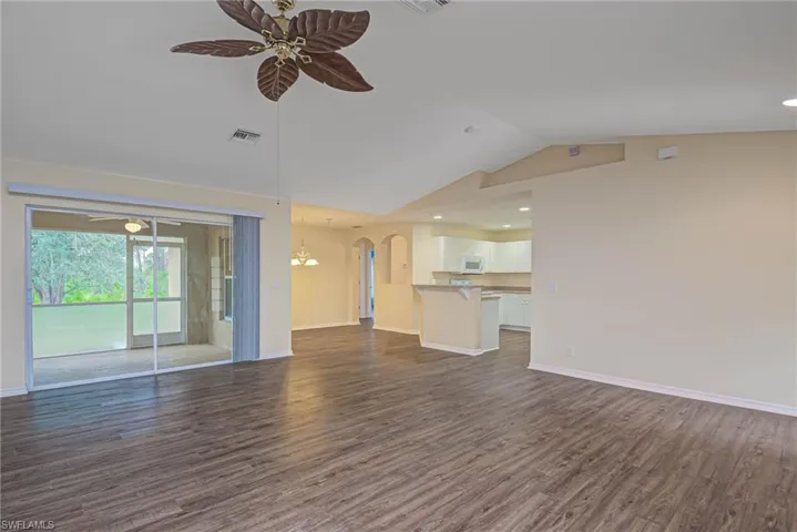 Unfurnished living room with ceiling fan, dark hardwood / wood-style flooring, and vaulted ceiling