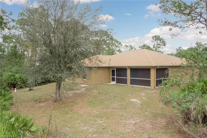 Rear view of property featuring a sunroom and a yard