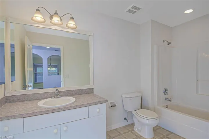Full bathroom featuring toilet, washtub / shower combination, and vanity