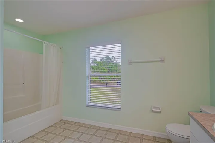 Full bathroom with toilet, shower / bathtub combination with curtain, and vanity