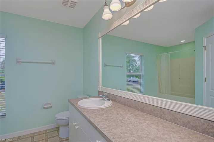 Bathroom with toilet, vanity, and a shower with curtain