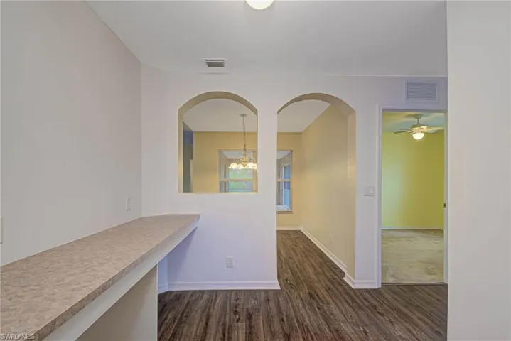 Hall with dark wood-type flooring and a chandelier