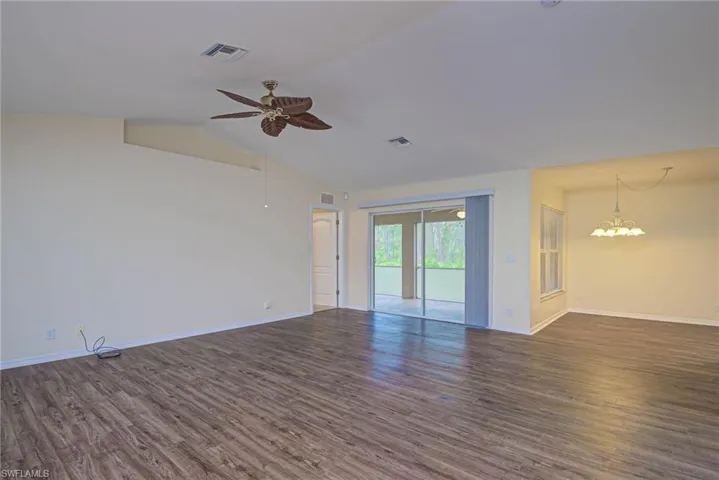 Spare room with lofted ceiling, dark hardwood / wood-style floors, and ceiling fan with notable chandelier
