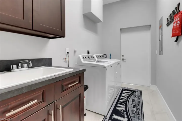 Washroom with baseboards, marble finish floor, a sink, washing machine and clothes dryer, and cabinet space