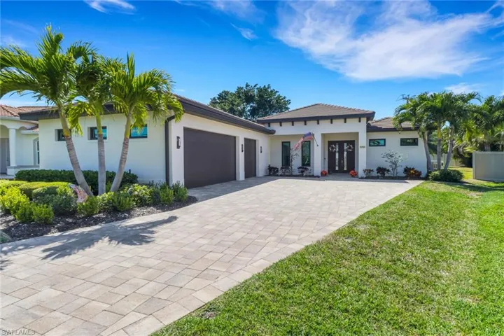 View of front of house with stucco siding, an attached garage, a front lawn, a tiled roof, and decorative driveway
