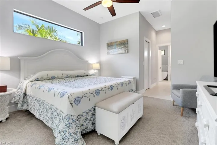 Bedroom with ceiling fan, visible vents, and light carpet