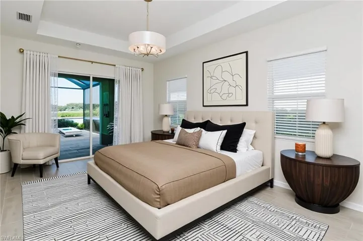 Bedroom with a raised ceiling, access to outside, and light wood-style flooring