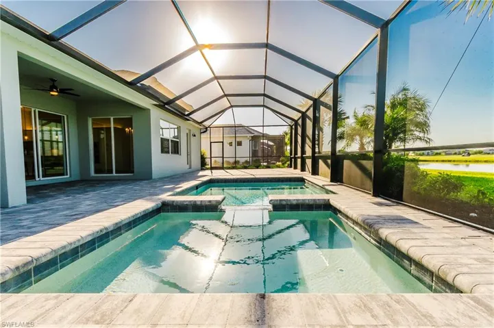 View of swimming pool featuring a pool with connected hot tub, a lanai, a patio, a sunroom, and a ceiling fan