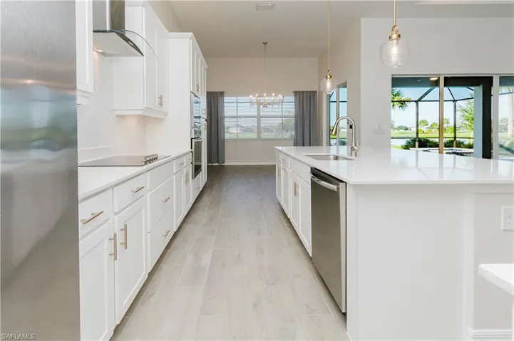 Kitchen with appliances with stainless steel finishes, white cabinets, and healthy amount of natural light