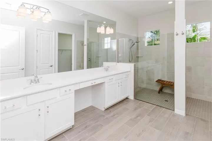 Full bathroom with a walk in shower, double vanity, wood finish floors, and a spacious closet
