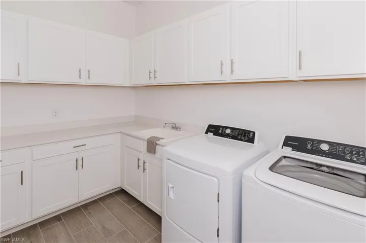 Laundry room featuring cabinet space, washing machine and clothes dryer, and wood tiled floors