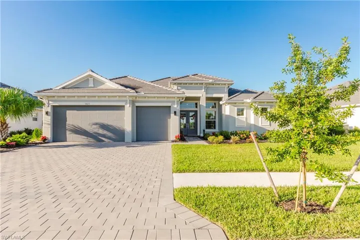 Prairie-style house with a front lawn, decorative driveway, a garage, stucco siding, and french doors