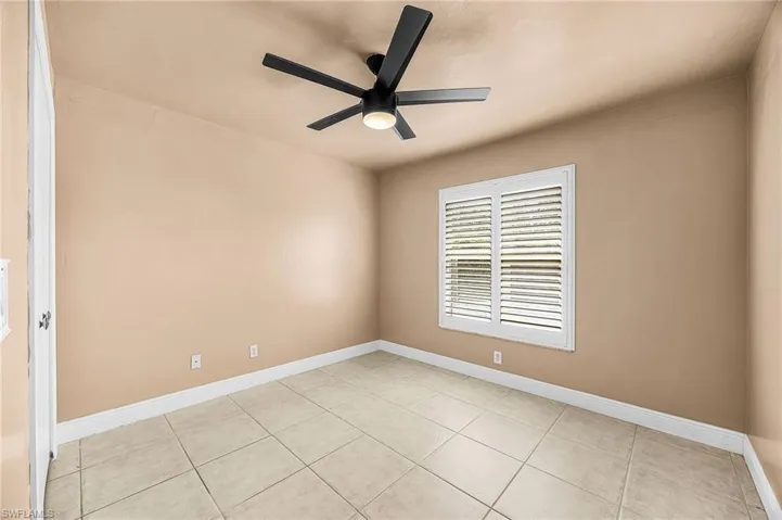 Empty room featuring a ceiling fan and light tile patterned flooring