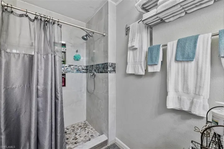 Bathroom featuring a stall shower and a textured wall
