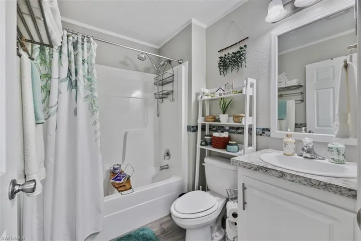 Bathroom with shower / bath combo with shower curtain, crown molding, and vanity