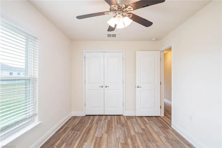 Unfurnished bedroom featuring light wood-style flooring, multiple windows, visible vents, and a closet