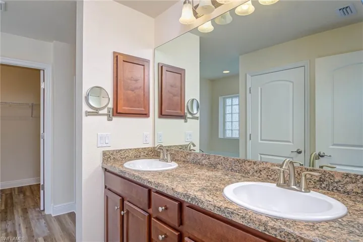 Bathroom with double vanity, visible vents, a sink, and wood finished floors