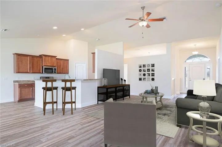 Living room featuring baseboards, light wood-style flooring, high vaulted ceiling, and ceiling fan