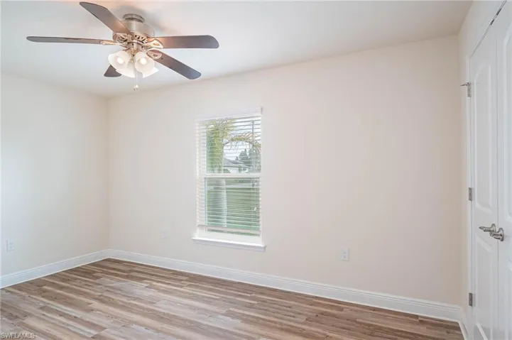 Spare room featuring light wood-style floors, ceiling fan, and baseboards