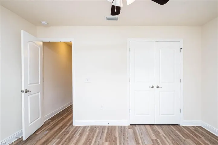 Unfurnished bedroom featuring a closet, visible vents, baseboards, and wood finished floors