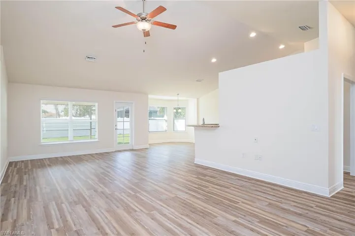 Unfurnished living room featuring light wood-style floors, visible vents, and vaulted ceiling