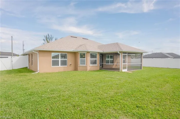 Back of property featuring a fenced backyard, a porch, roof with shingles, a lawn, and stucco siding