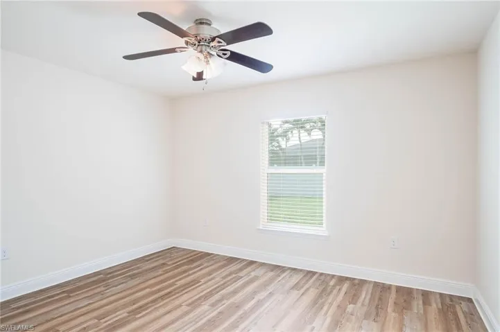 Empty room with a ceiling fan, baseboards, and light wood finished floors