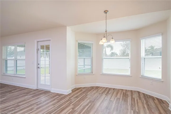 Unfurnished dining area with light wood finished floors, baseboards, and a chandelier