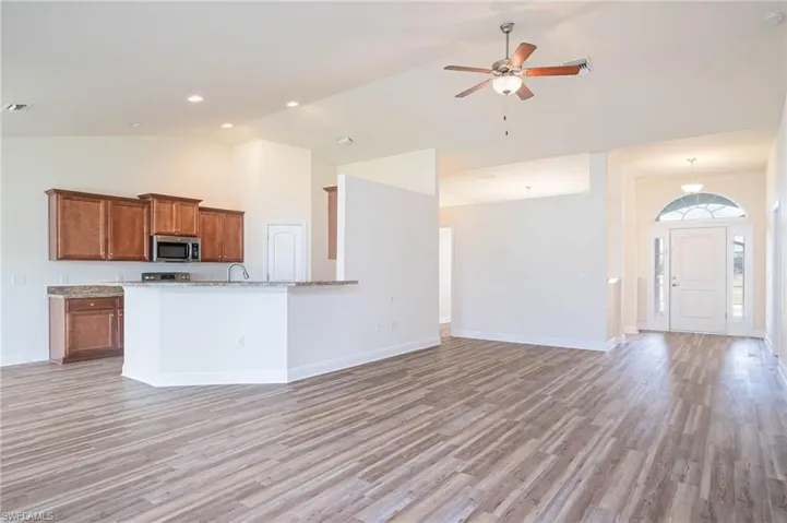 Kitchen featuring light wood-style flooring, stainless steel microwave, brown cabinets, and open floor plan