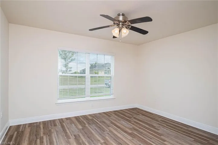Unfurnished room featuring ceiling fan, wood finished floors, and baseboards