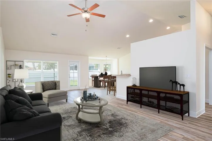 Living area with visible vents, light wood-type flooring, a ceiling fan, and vaulted ceiling