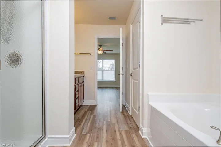 Full bath featuring a soaking tub, wood finished floors, vanity, visible vents, and a shower stall