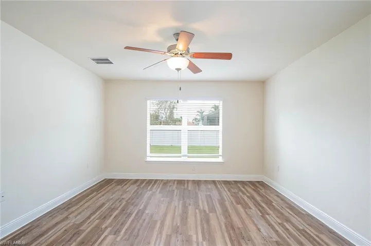 Empty room featuring light wood finished floors, baseboards, visible vents, and a ceiling fan