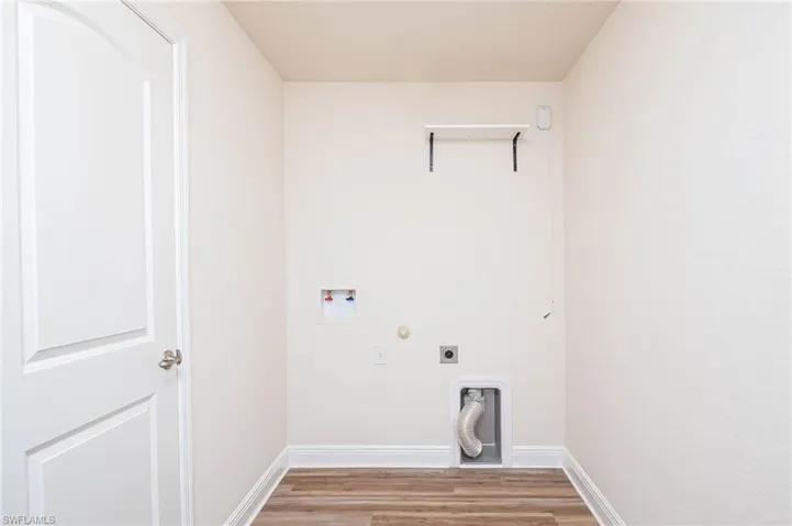 Laundry area featuring hookup for a washing machine, laundry area, baseboards, light wood-type flooring, and electric dryer hookup