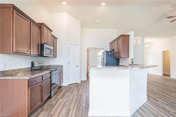 Kitchen with a peninsula, appliances with stainless steel finishes, light wood-type flooring, and a sink