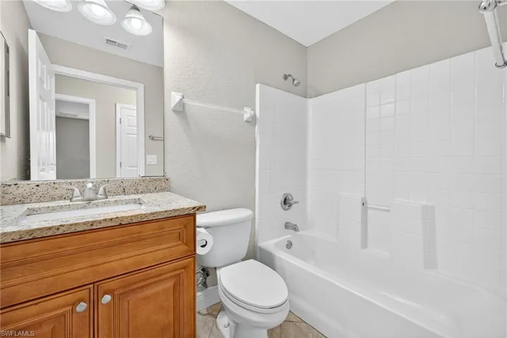 Full bathroom featuring a textured wall, tub / shower combination, and vanity