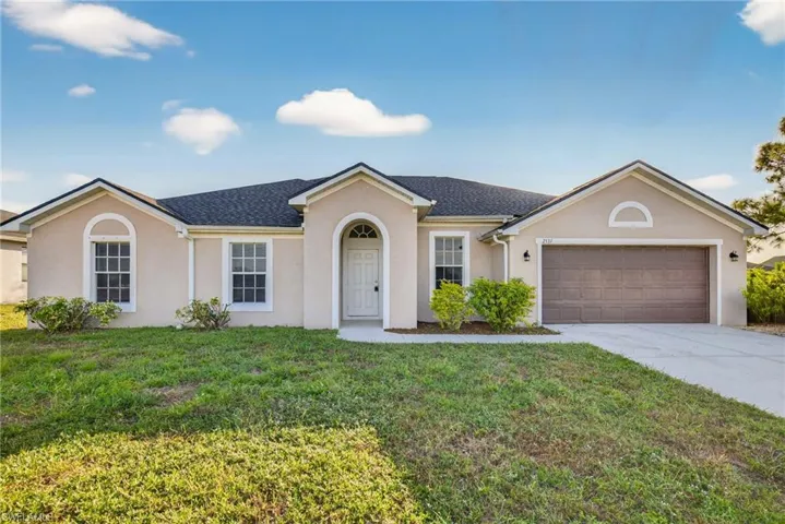 Ranch-style home with stucco siding, a front yard, driveway, and a shingled roof