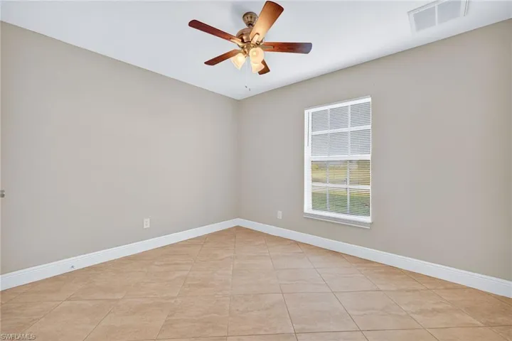 Empty room with light tile patterned floors and a ceiling fan